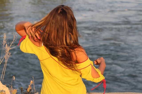 Girl throwing hair behind shoulder by a lake